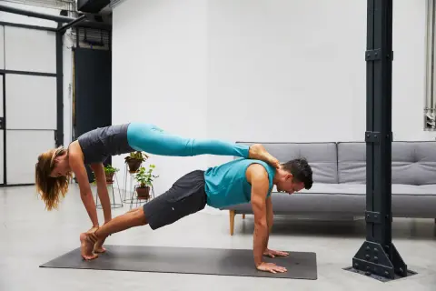 Paar übt anspruchsvolle Acroyoga Figuren. Sie bilden eine stabile Basis für kreative Posen.