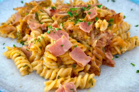 Ein köstlicher Nudelauflauf mit Spiralnudeln, Schinken und Käse, garniert mit Petersilie.