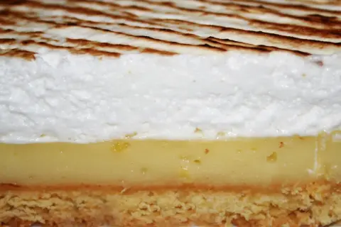 Tranche de tarte au citron avec une généreuse couche de meringue italienne dorée.
