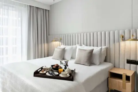 Eleganckie łóżko w pokoju hotelowym, śniadanie na tacy, jak w Royal Tulip Warszawa.