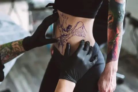 Tätowierer bereitet Motiv vor. Nach dem Stechen ist die Frage: wie lange tattoo mit Bepanthen eincremen?