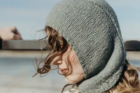 Una joven con un gorro tejido gris, que recuerda al balaclava origen, mira al horizonte.