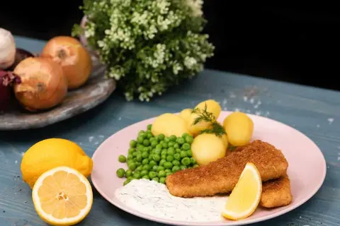 Panerad fisk med kokt potatis, gröna ärtor och en krämig sås som påminner om skolans kalla fisksås. Serveras med citron.