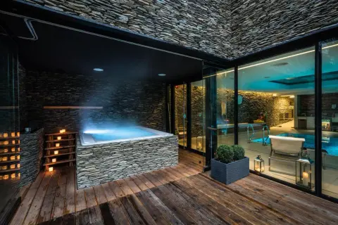 Luksusowy wrocław hotel z basenem i jacuzzi na zewnątrz. Kamienne wykończenia, drewniany taras i nastrojowe oświetlenie tworzą relaksującą atmosferę.