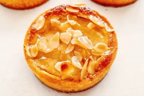 Tarte poire amandine dorée, garnie d'amandes effilées et d'un glaçage brillant. Un délice croustillant et fruité.