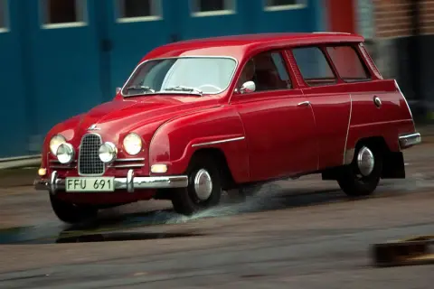 Röd Saab 2-takt kombi kör genom vattenpölar.