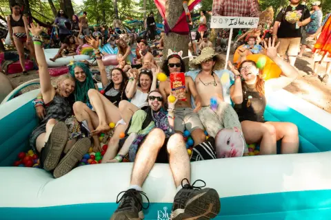 A group of friends enjoys a ball pit at the lil dub festival, laughing and posing for a photo.