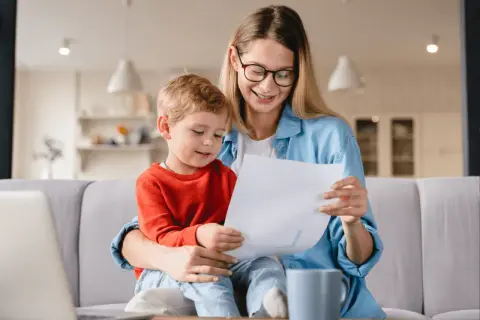 Mama z synkiem aktywnie w domu dla kogoś, przeglądają dokumenty.