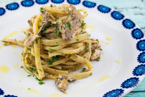 Un plat de pâtes linguine garni de sardines émiettées, de persil frais et de chapelure, un délice de pasta con le sarde.