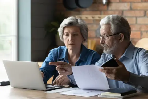 Para, mam 60 lat i 10 lat pracy, czy dostanę emeryturę? Zastanawiają się nad tym, analizując dokumenty i dane na laptopie.