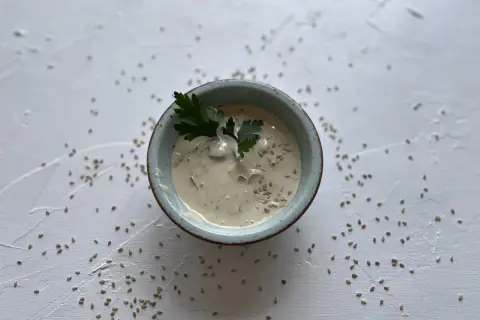 Cremige Sauce in einer Schale, garniert mit Petersilie und Sesam. Was ist Tahin? Eine köstliche Sesampaste, die hier als Dip serviert wird.