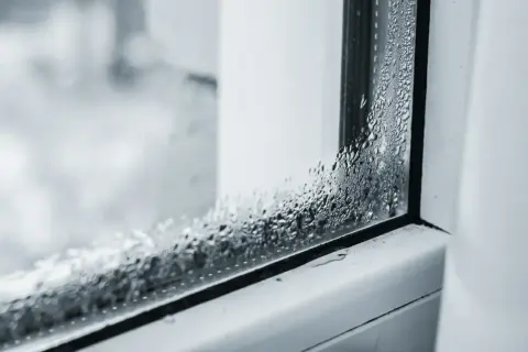 Krople wody na szybie okiennej, które pokazują, dlaczego parują szyby w domu.