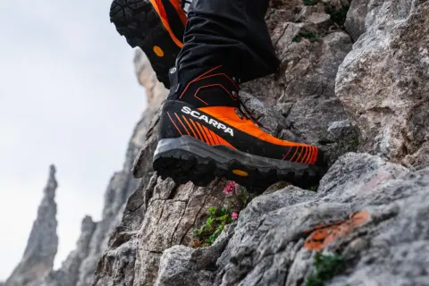 Des chaussures de randonnée Scarpa orange et noires, parfaites pour choisir son chemin sur les rochers escarpés.