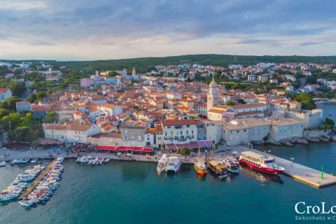 Malownicze miasteczko Krk w Chorwacji z portem pełnym łodzi i kamiennymi budynkami pod czerwonymi dachami.