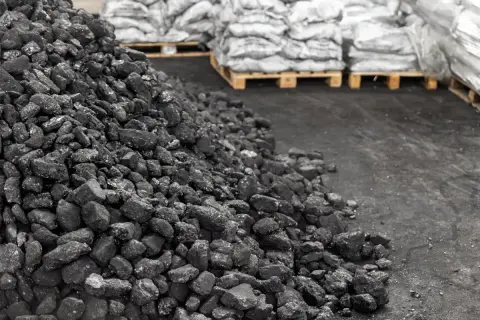 Góra węgla na składzie, obok palety z workami. Aktualna cena węgla na składach budzi niepokój.