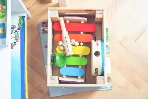 Kolorowy kącik matematyczny z cymbałkami, żabką i tamburynem w drewnianej skrzynce.
