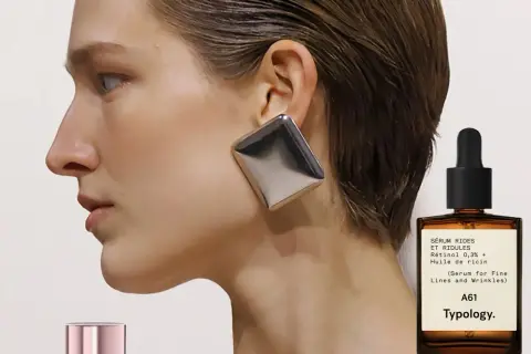 Frau mit auffälligem Ohrring und einem Fläschchen Retinol-Serum. Ab wann Retinol? Typology A61 für feine Linien.