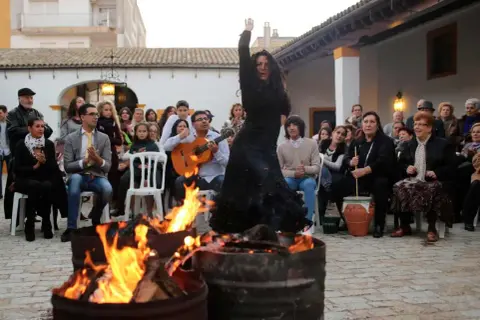 Bailarina flamenca actuando junto a hogueras, con guitarrista y público. Ambiente de villancicos flamencos jerezanos.