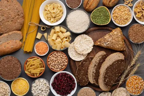 Różnorodne produkty zbożowe: chleb, makaron, ryż, kasze, nasiona i płatki.