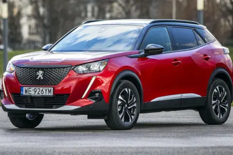 Czerwony Peugeot 2008 na zewnątrz. Wiele osób szuka peugeot 2008 opinie, by dowiedzieć się więcej o tym modelu.