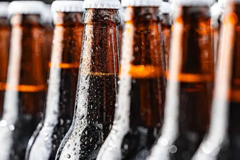 Bottiglie di birra ambrata, bagnate di condensa, perfette per chi cerca una birra piccola calorie.