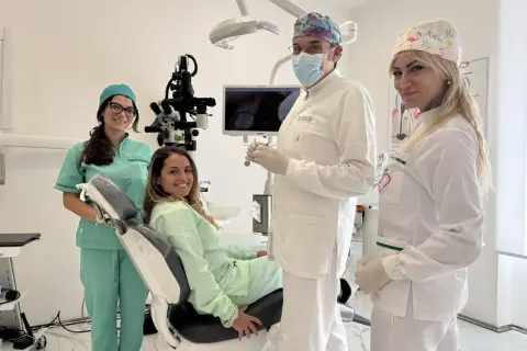 Sorrisi in clinica: un dentista, due assistenti e una paziente felice. La prima visita dal dentista si paga, ma la salute orale è un investimento.