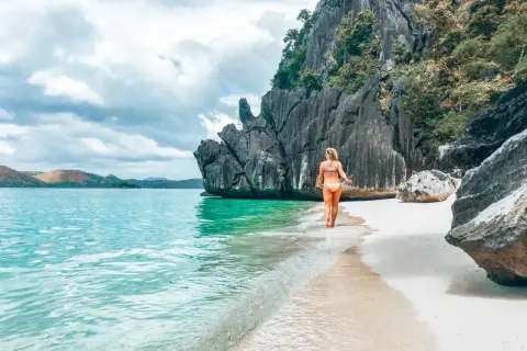 Frau genießt das türkisfarbene Wasser und den weißen Sandstrand auf den Philippinen. Ein perfekter Ort für Backpacking-Abenteuer.