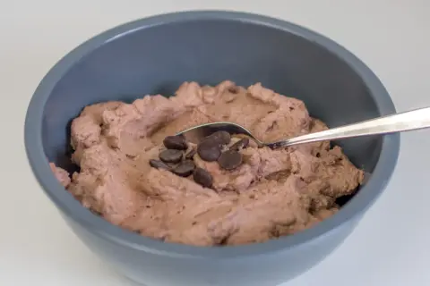 Schokoladige Sahnecreme mit Schokodrops in einer grauen Schüssel, bereit zum Genießen.