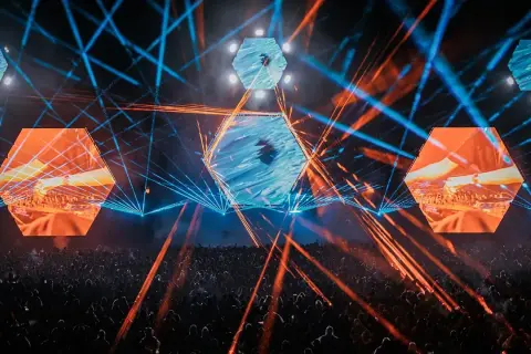 Energetyczna scena z laserami i ekranami w kształcie heksagonów. Tłum bawi się na koncercie, który zapowiada się na niezapomniane **Audioriver 2026**.
