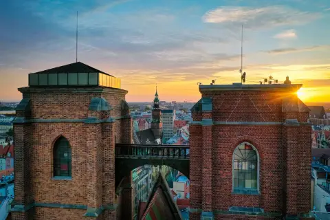 Zachód słońca nad Wrocławiem, widok na Most Czarownic między ceglanymi wieżami.