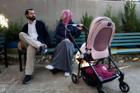 En man och en kvinna, som representerar muslimer i Sverige, sitter på en bänk med en barnvagn.