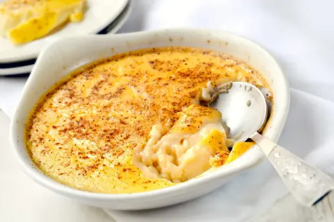 Un déliceux dessert crémeux, des oeufs au lait saupoudrés de cannelle, prêts à être dégustés avec une cuillère en argent.