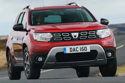 Röd Dacia Duster begagnad kör på en landsväg.