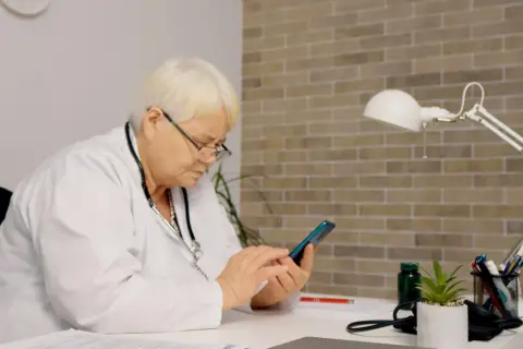 Lekarka sprawdza na telefonie, jak długo jest ważne skierowanie do szpitala.