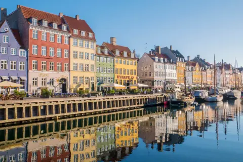 Kolorowe kamienice nad kanałem Nyhavn to obowiązkowy punkt na mapie kopenhaga co zobaczyć. Widać tu odbijające się w wodzie łodzie i budynki.