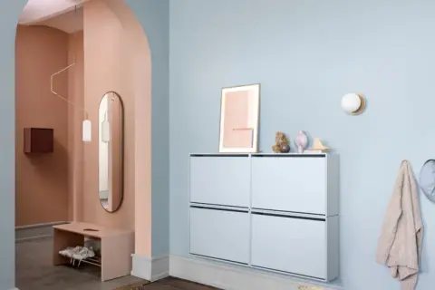 Sanfter Flur mit Wand in Rosé und Hellblau. Moderne Schuhschränke und eine Bank bieten praktische Aufbewahrung. Tolle flur farbe ideen für ein einladendes Ambiente.