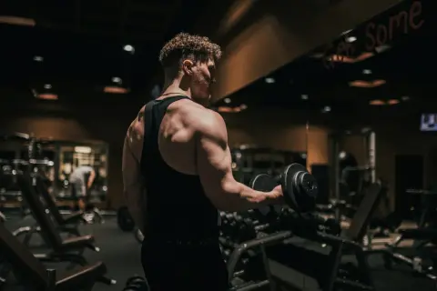 Mężczyzna ćwiczy biceps z hantlem w siłowni. To dowód, jak crossfit zmienił moje życie, budując siłę i pewność siebie.