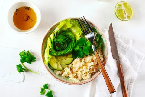 Un fresco e colorato cous cous freddo con avocado a spirale, cetrioli, lattuga e erbe aromatiche.
