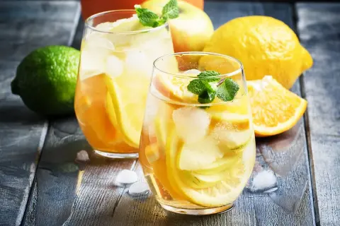 Två glas med uppfriskande vit sangria, fyllda med äppel- och citrusskivor, is och mynta. Perfekt för ett somrigt vit sangria recept.