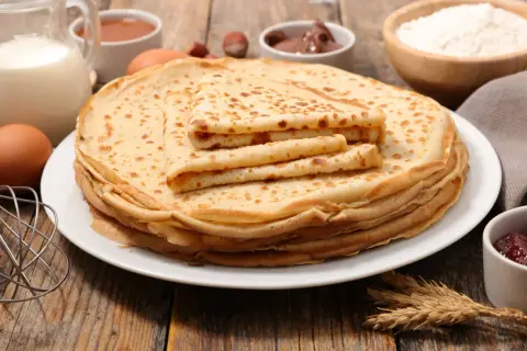 Una pila de crepes dorados, con ingredientes como leche, huevos y harina, evocan el origen de los crepes, un manjar sencillo y delicioso.