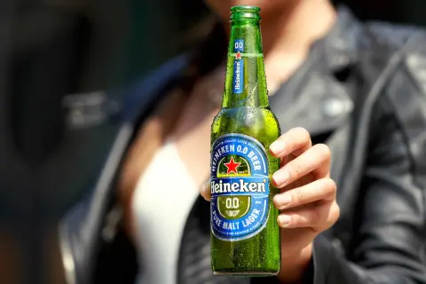 Mano che tiene una bottiglia di Heineken 0.0, la birra senza glutine, rinfrescante e gustosa.