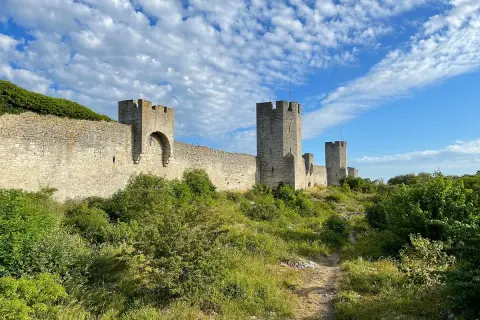 Imponerande ringmur med torn, en av de mest sevärda platserna att se i Visby. Grönskande natur längs muren.