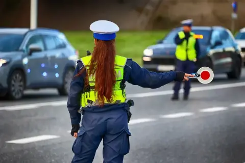 Policjantka kieruje ruchem, trzymając tarczę. Kierowcy powinni znać taryfikator mandatów, by uniknąć nieprzyjemności.