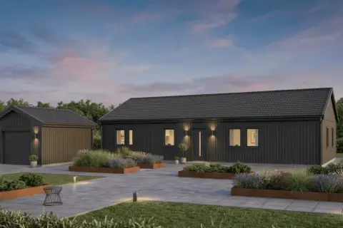 Modern dark gray house and detached garage with landscaped garden beds and paved driveway at dusk.