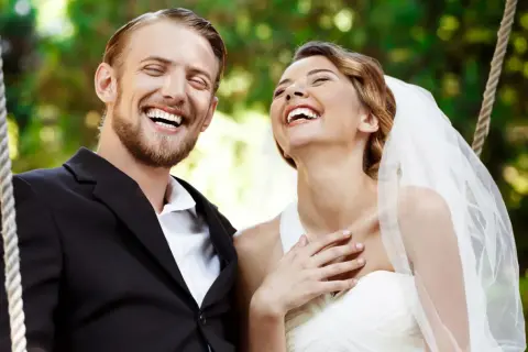 Coppia felice ride su un'altalena, perfetta per frasi per matrimonio e battesimo insieme.