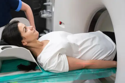 Frau liegt auf Liege für PET-CT-Untersuchung. Rote Laserlinien markieren Position.