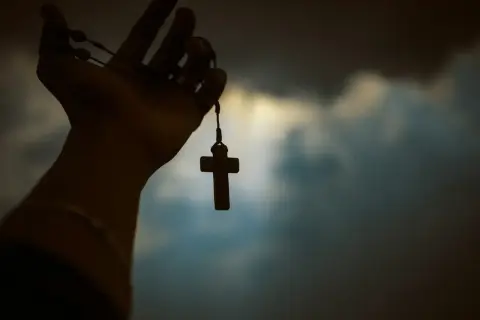 Dłoń trzyma paciorki różańca z krzyżem. Czy to symbol wiary, czy wątpliwości agnostyka, a może wyraz buntu ateisty?