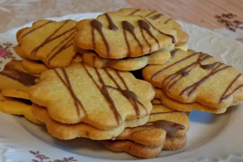 Stos ciastek z marmoladą, ozdobionych czekoladowymi paskami, wygląda apetycznie.