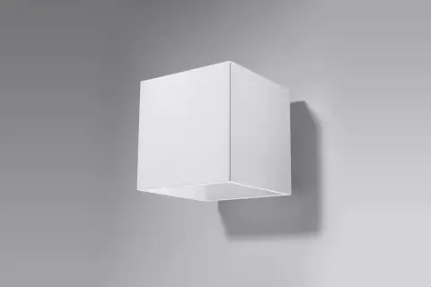 Minimalistyczna lampa kostka w kolorze białym, zamontowana na szarej ścianie. Rzuca subtelny cień.