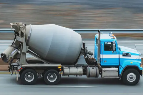 Niebieska betoniarka pędzi po drodze. Zastanawiasz się, ile kosztuje beton?